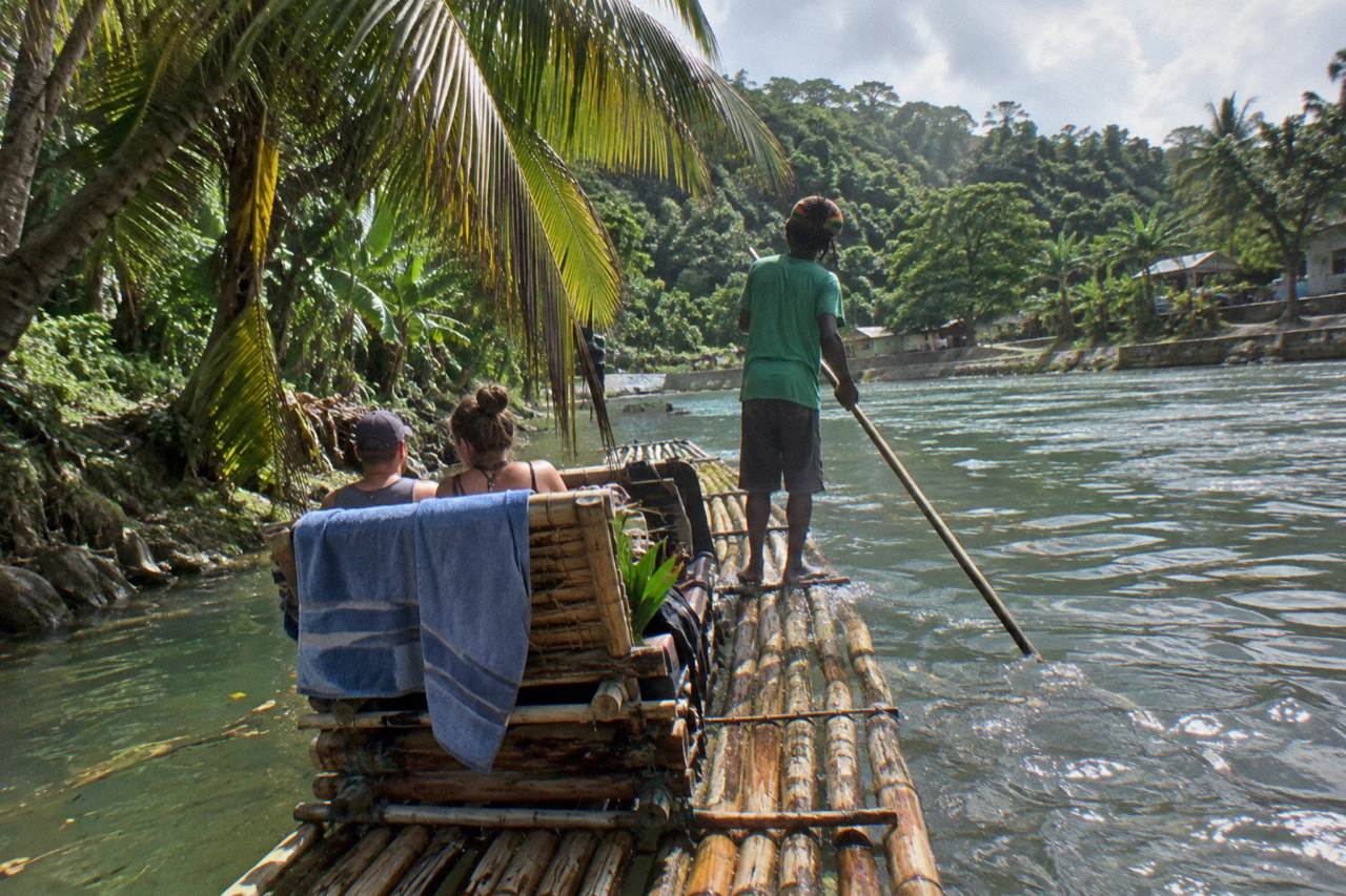 A bamboo raft resting on a calm green river beside overhanging trees