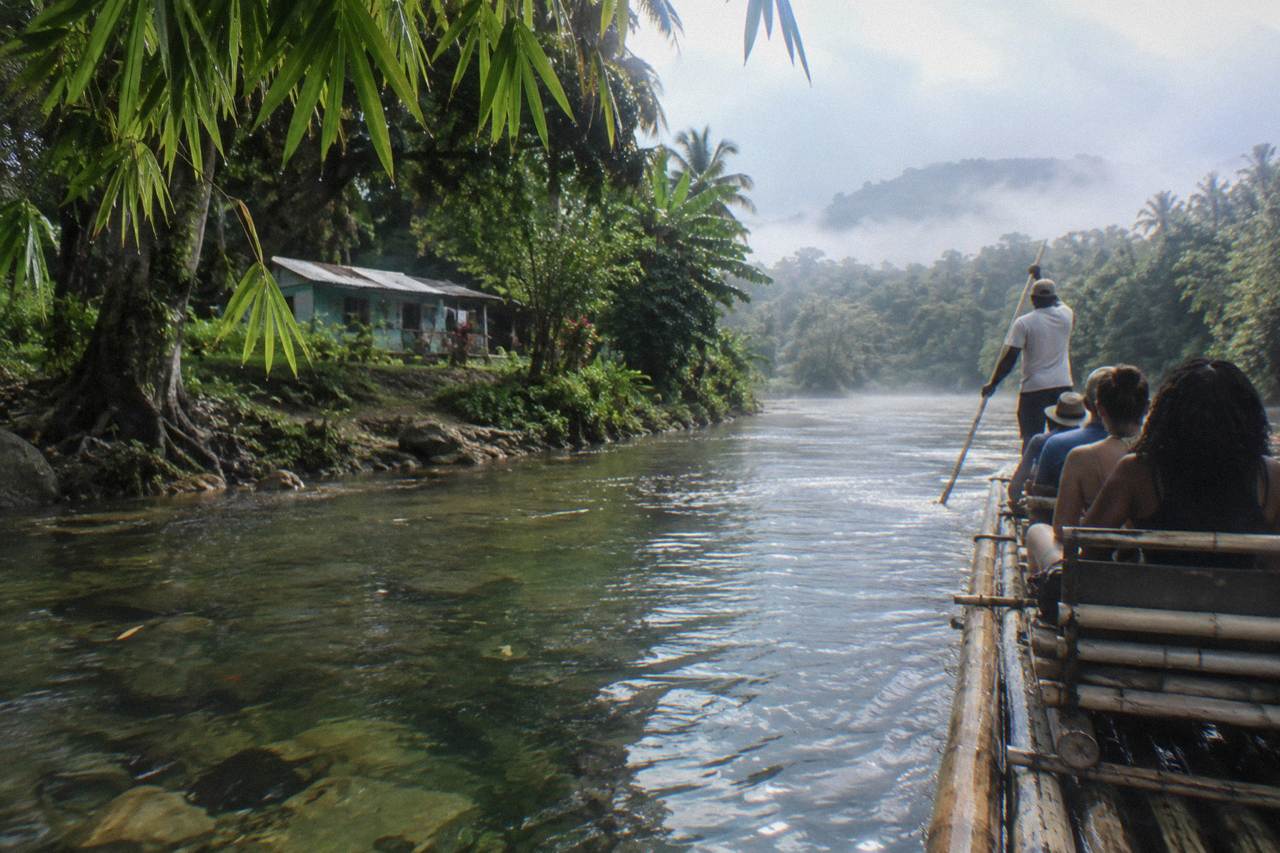 A long bamboo raft drifting slowly on a still green jungle river in Jamaica