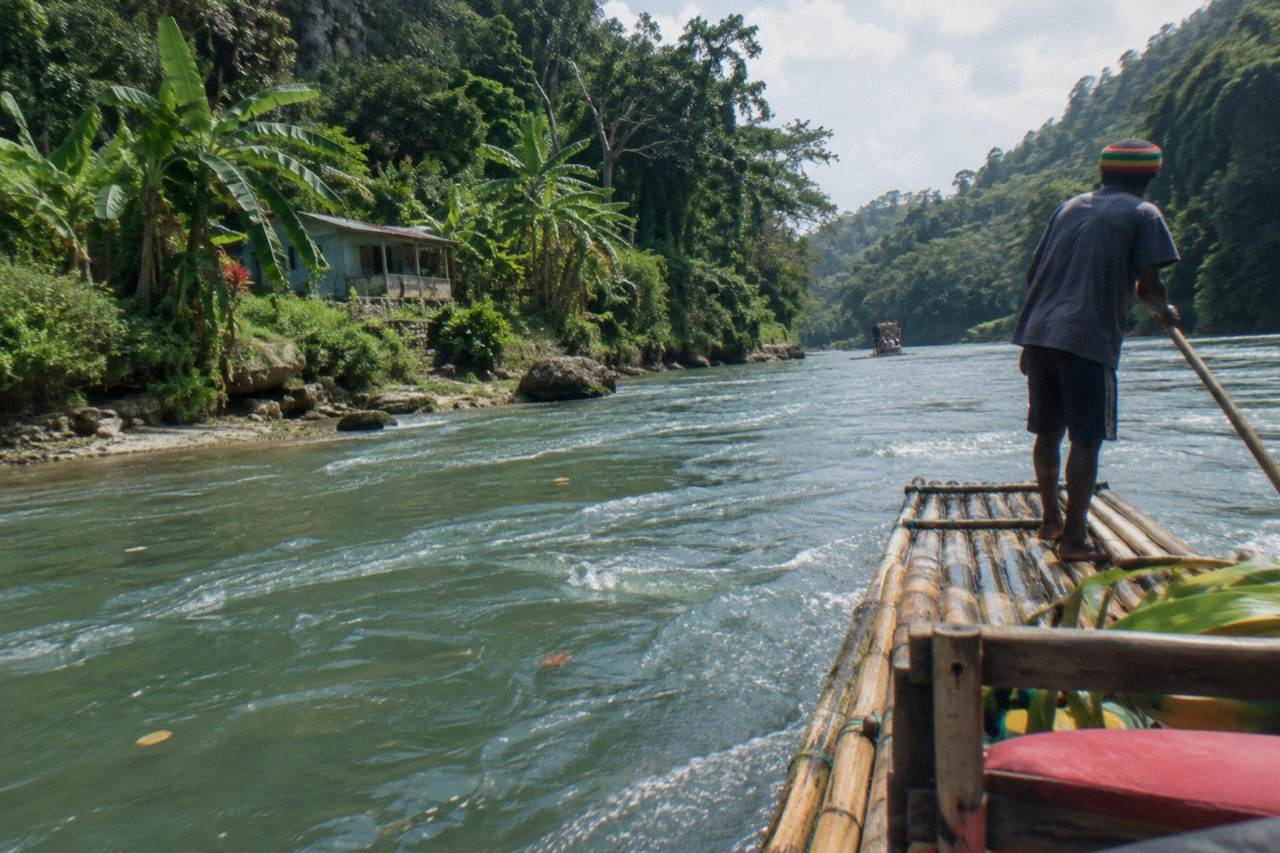 A calm tropical river winding between forested green hills under a bright sky