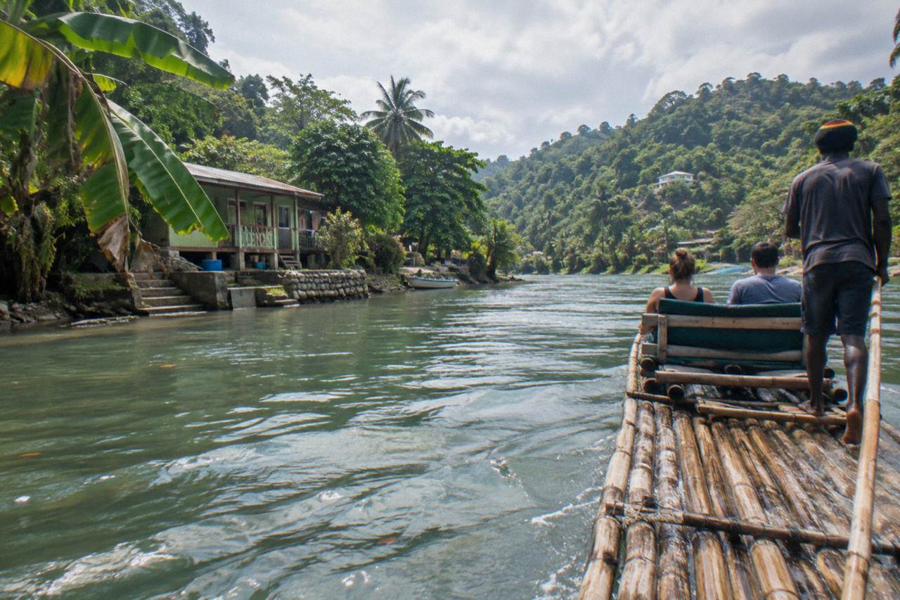 A bamboo raft drifting on a calm green river between forested banks in Portland