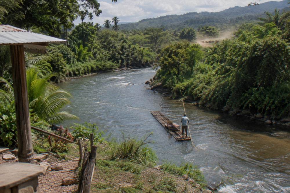 A wide slow river bending through green hills with dense vegetation on both banks