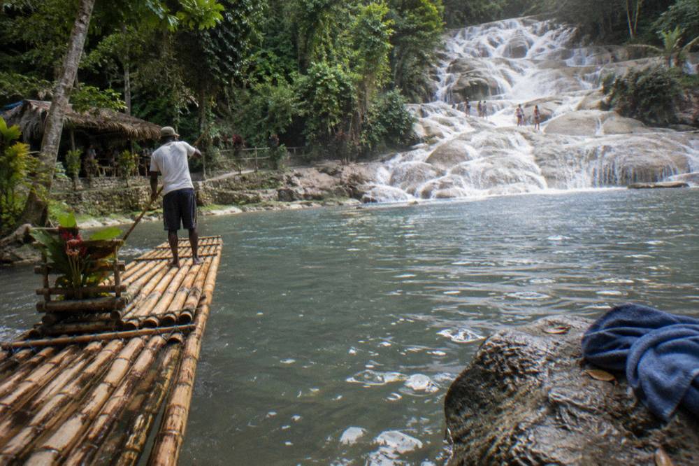 A tall terraced waterfall fanning over pale rock steps into a wide pool