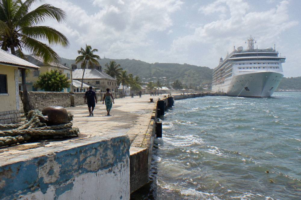 A cruise ship docked beside a historic waterfront town at midday