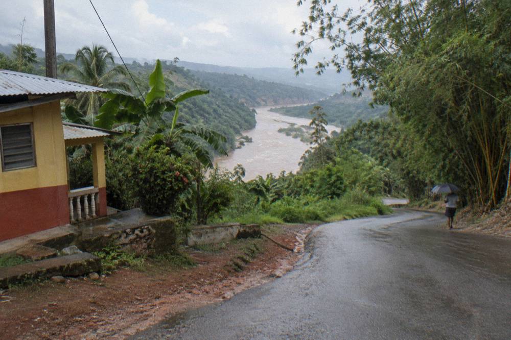 A winding rural road through dense green hills toward a river valley