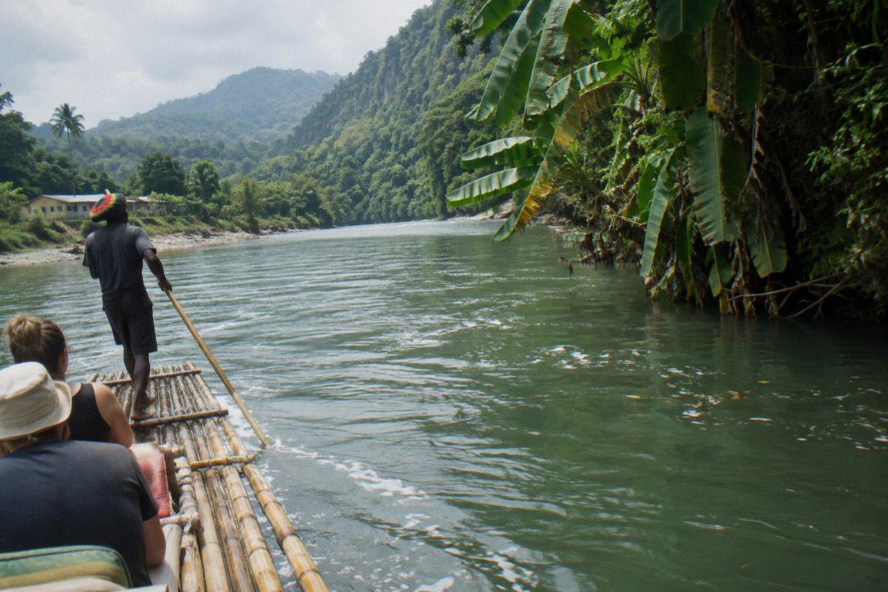 A bamboo raft drifting on a wide green river between forested hills in Portland