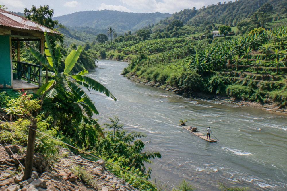 A wide calm river bending between green hills under a bright sky