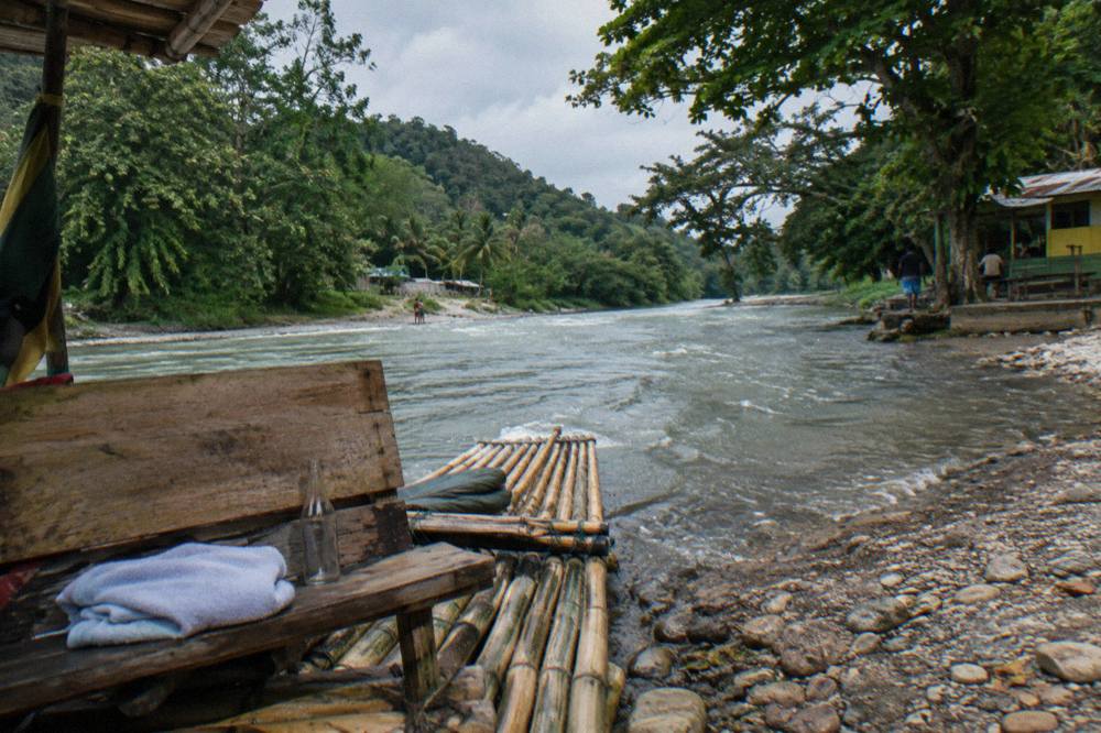 A bamboo raft resting at a quiet riverbank landing surrounded by dense tropical trees