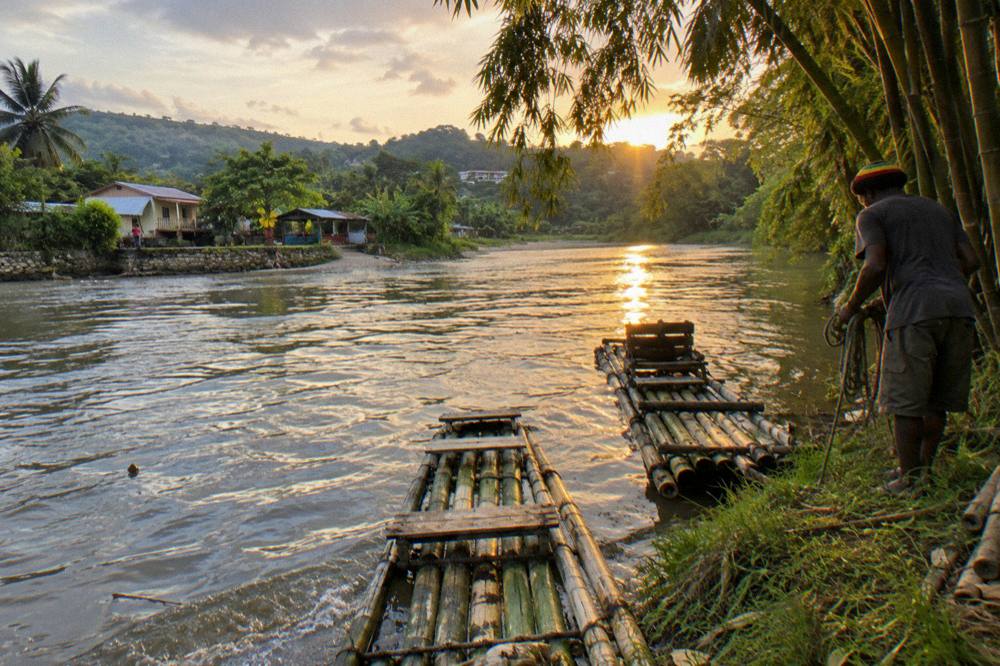 A calm river bend at golden hour with bamboo rafts moored along a quiet bank
