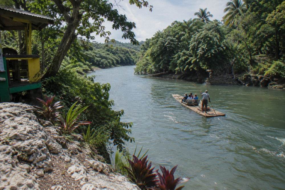A calm wide river bending between tree covered banks in Jamaica