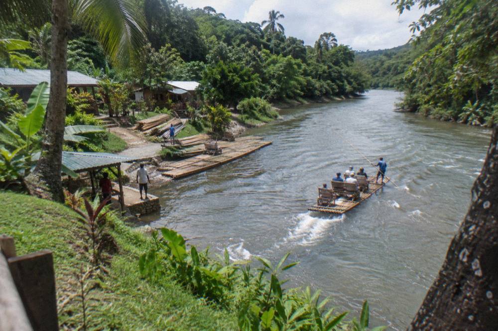 Winding river through dense green forest with a wooden raft launching point on the bank
