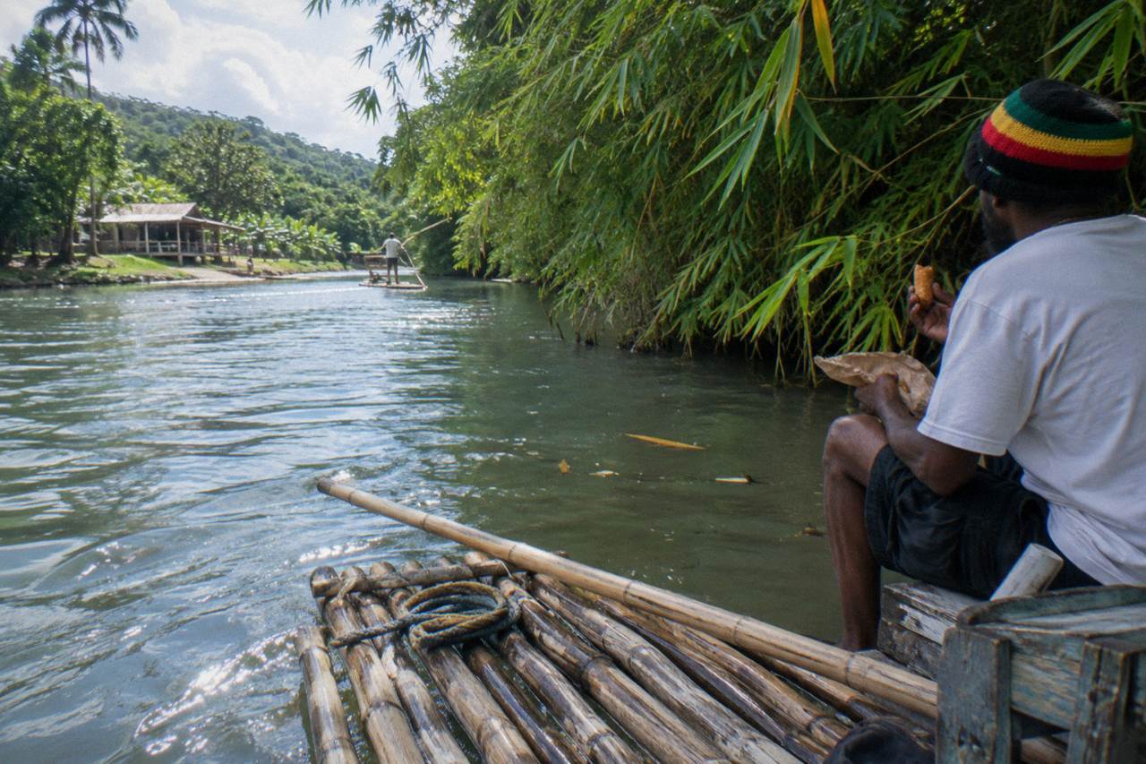 Bamboo raft resting on a calm green river beside overhanging trees