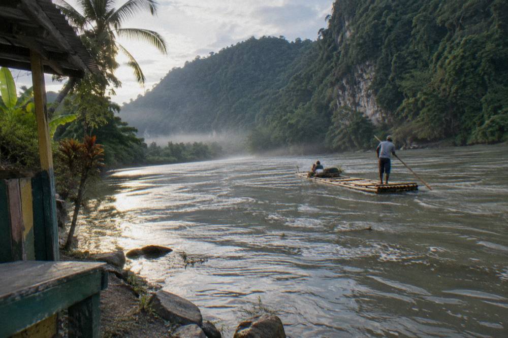 Morning light on a wide slow river curving between forested hills