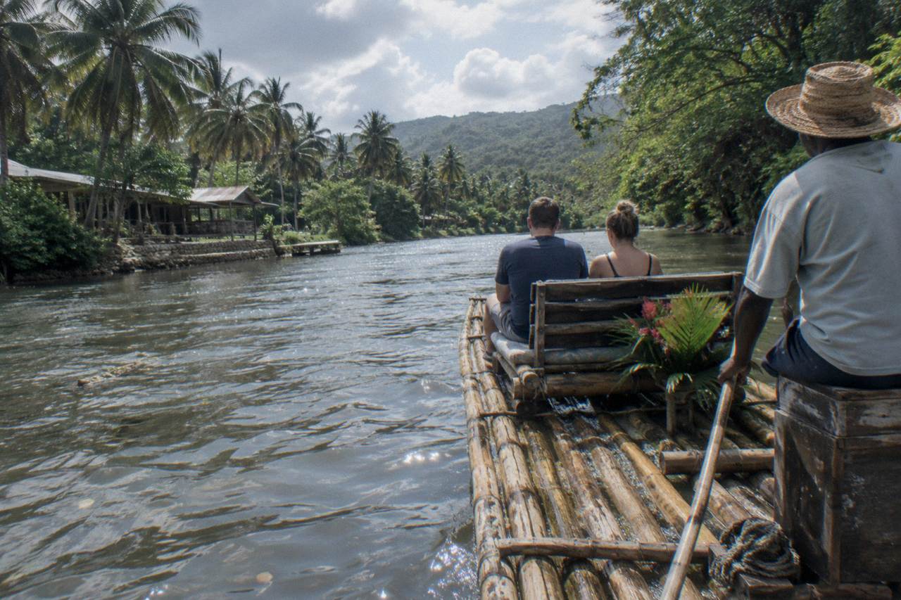 A long bamboo raft resting on a calm Jamaican river between green banks
