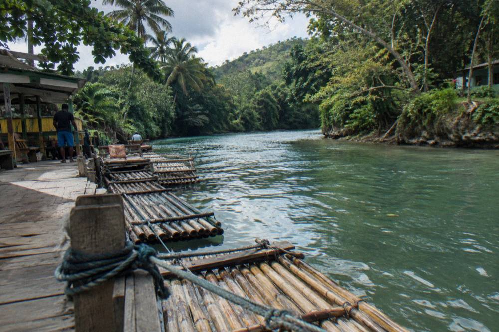 A calm river bend with bamboo rafts tied along a wooden dock