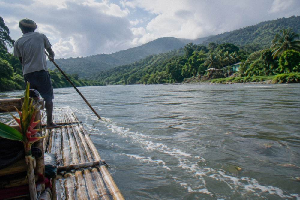 A wide slow river seen from the water with green hills in the distance