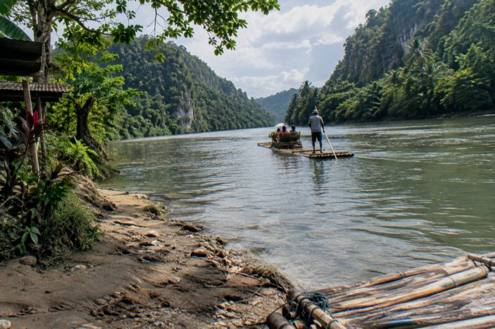 Sunlight on a wide calm river with green valley slopes rising on both sides