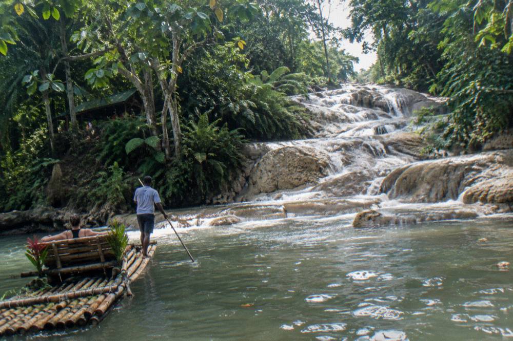 Terraced waterfall steps winding through tropical vegetation toward a pool below