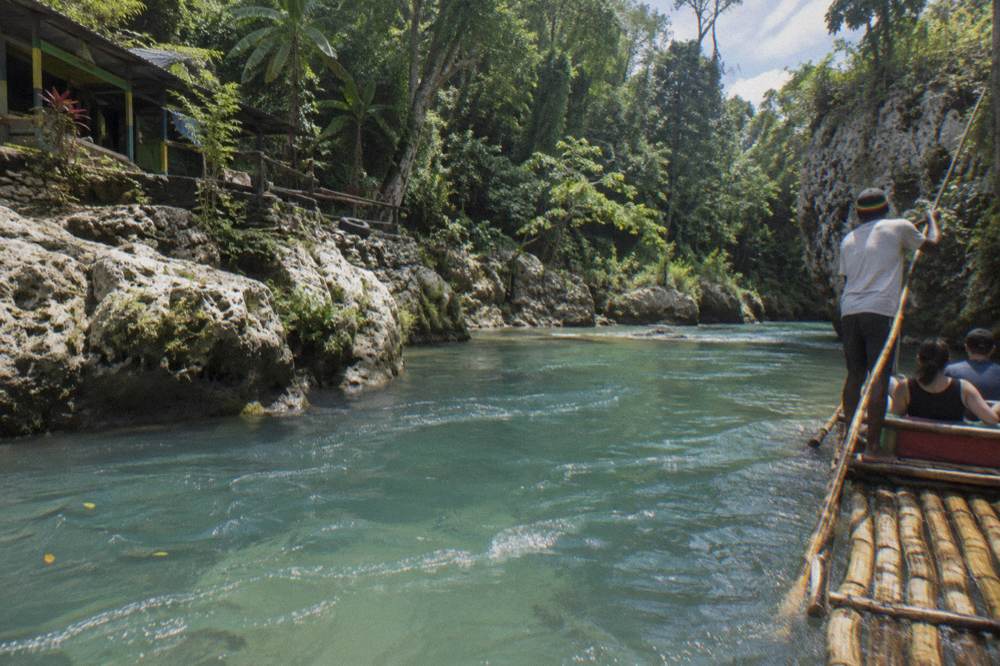 Turquoise river pool ringed by limestone rocks and dense green forest