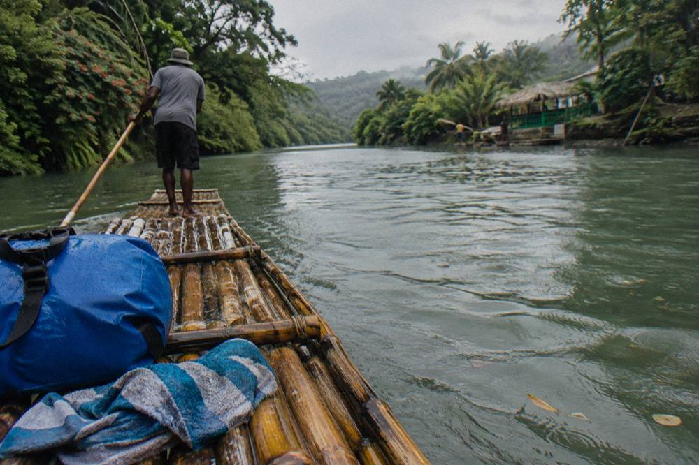 A dry bag and towel resting on the bamboo platform of a raft