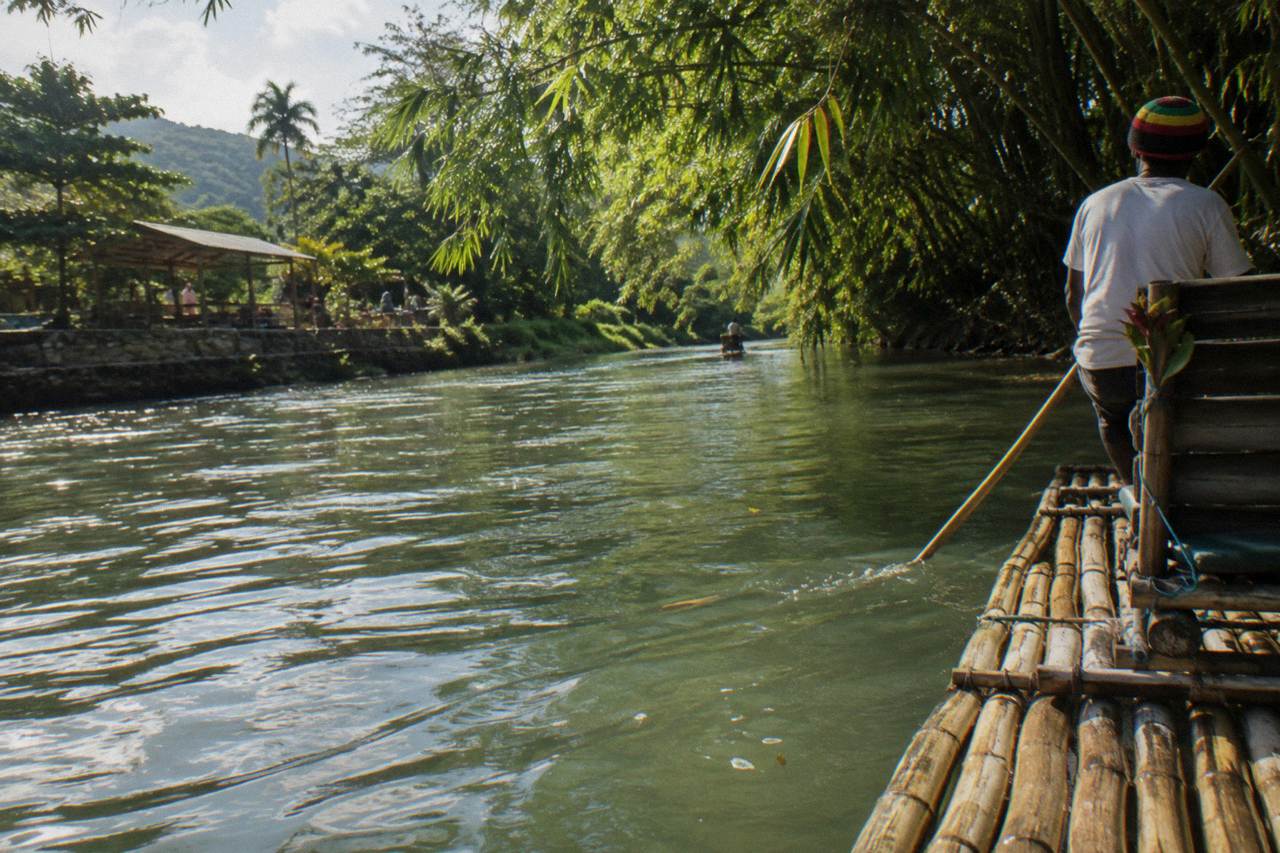 A bamboo raft resting on a calm green Jamaican river beneath overhanging trees