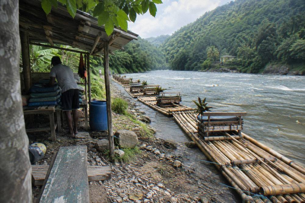 Bamboo rafts moored along a riverbank in a green valley