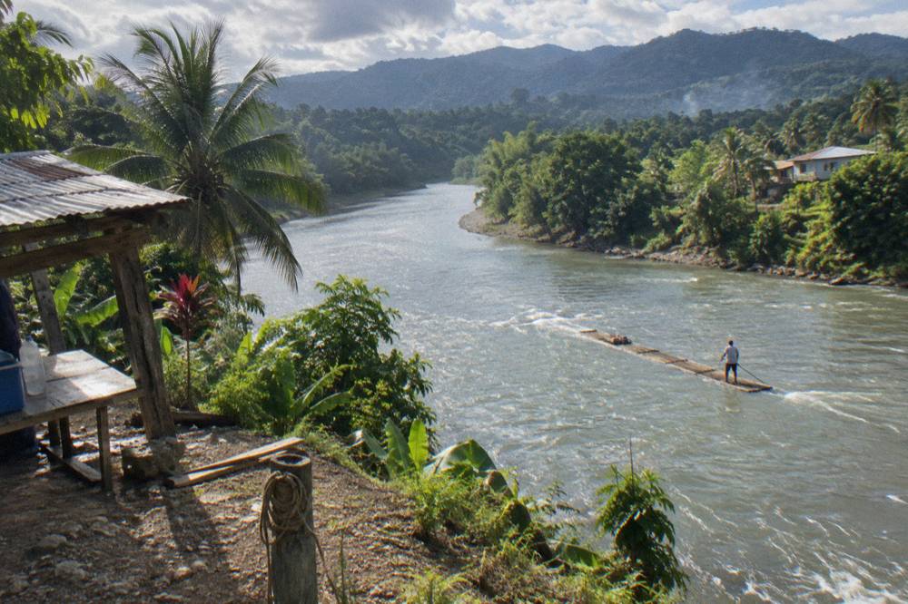 A wide slow river curving through a green valley with hills on the horizon in eastern Jamaica