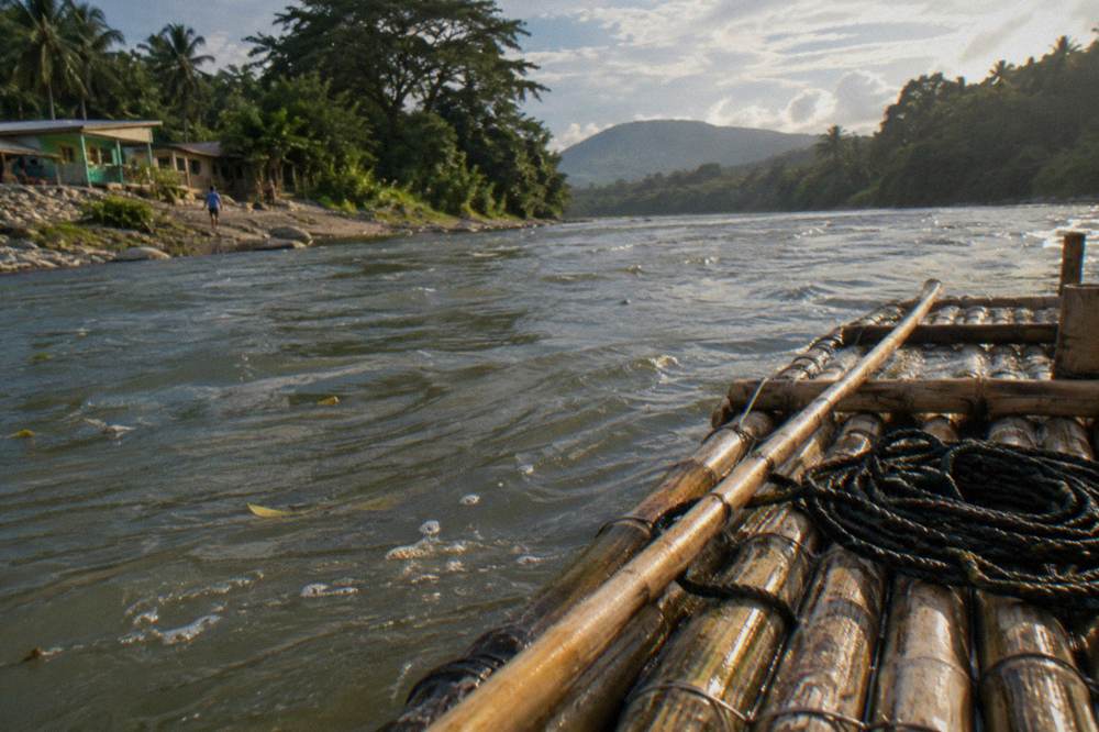 A close view of woven bamboo raft decking with a long wooden pole resting across it