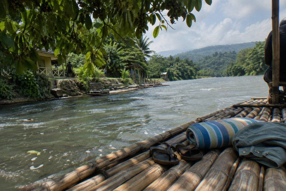 A moored bamboo raft resting on the calm water of a Jamaican river