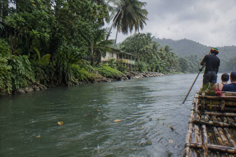 A bamboo raft resting at a river bank with dense green forest on both sides of calm water